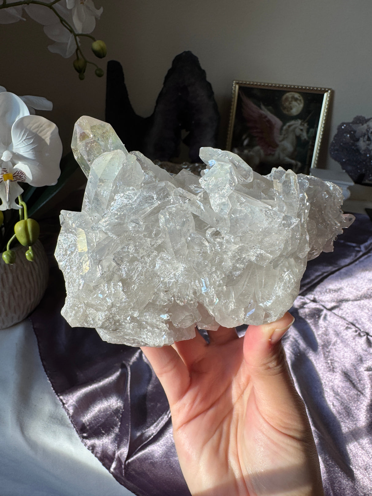 Hand holding a large crystal with a blurred indoor background
